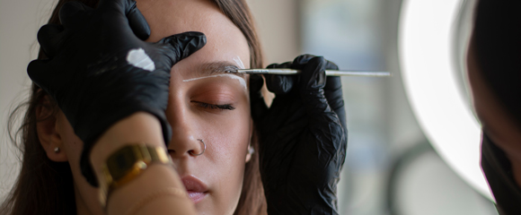 The brow artist prepares the model for the application of eyebrow dye